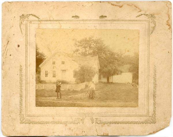 Man & Woman with Bicycle in Front of Home