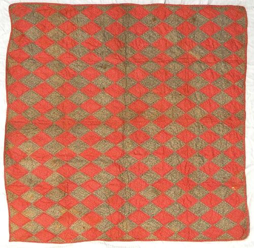 Crib quilt in patchwork diamond pattern, alternating between a light print on red cotton and a …