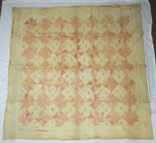 Quilt with one side pieced in alternating pinwheel and plain blocks.