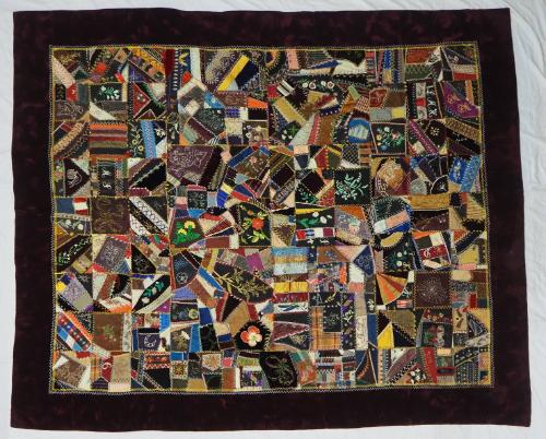 Crazy quilt with pieces of various colors and weaves of silk, with border of very dark plum sil…