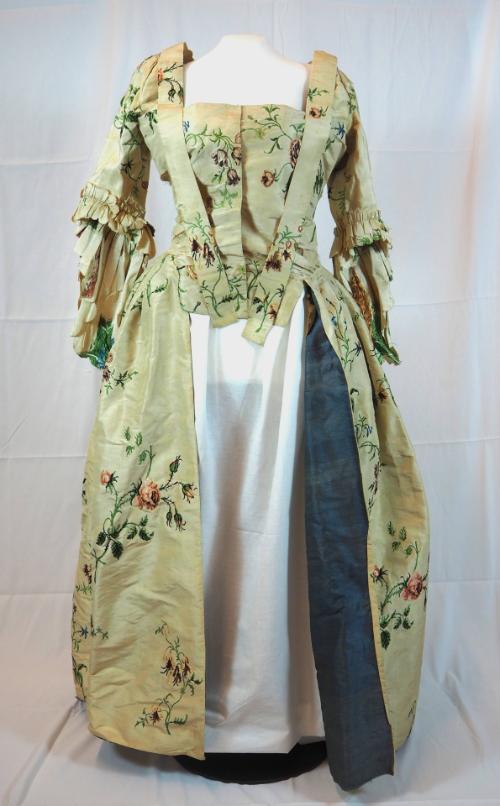Fitted gown of brocaded silk, seen from the front, with front edge of skirt turned out slightly…