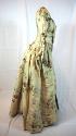 Fitted gown of brocaded silk, seen from the side.
