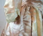 Close-up of bottom of sleeve of pink satin gown, with white satin trim.