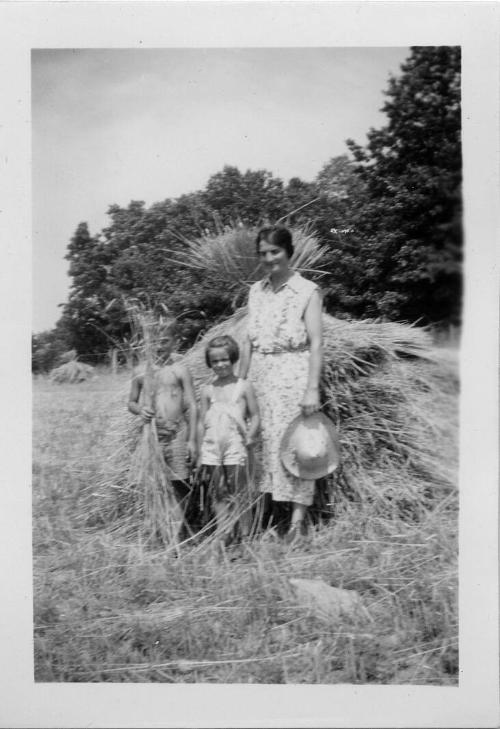 Two Children and a Woman in Front of a Haystack