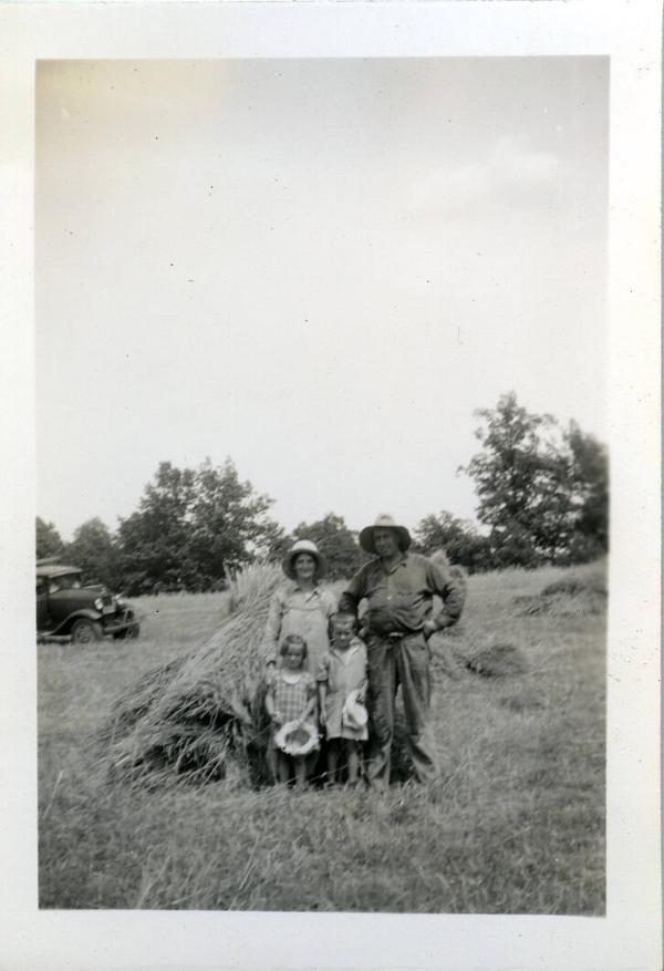 Two Dezemo Children with Adults in a Hay Field