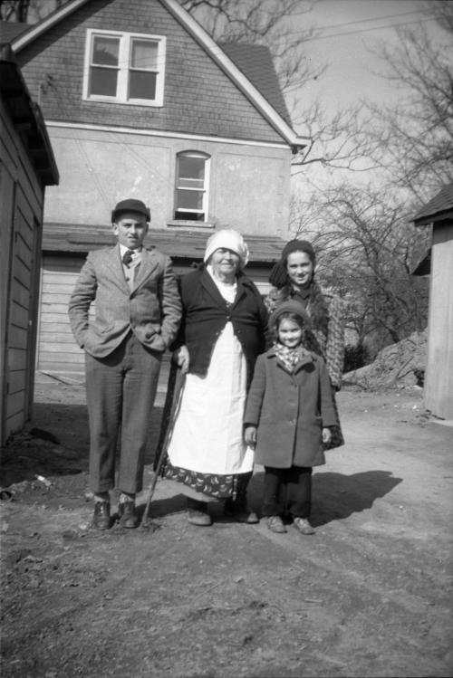 Grandma with George, Anna and Myrtle Dezemo Near a House