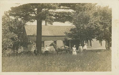 Men, Woman, and Horse in Front of House