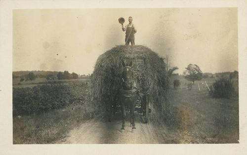 Man on a Wagon of Hay Waving his Hat