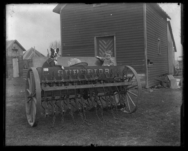 Child and Dog seated in a Grain Drill