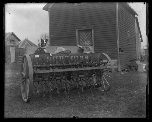 Child and Dog seated in a Grain Drill