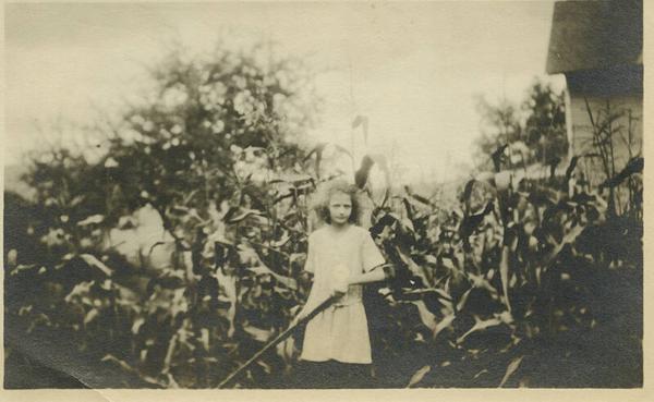 Girl Holding Tool in Front of Corn
