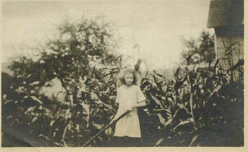 Girl Holding Tool in Front of Corn